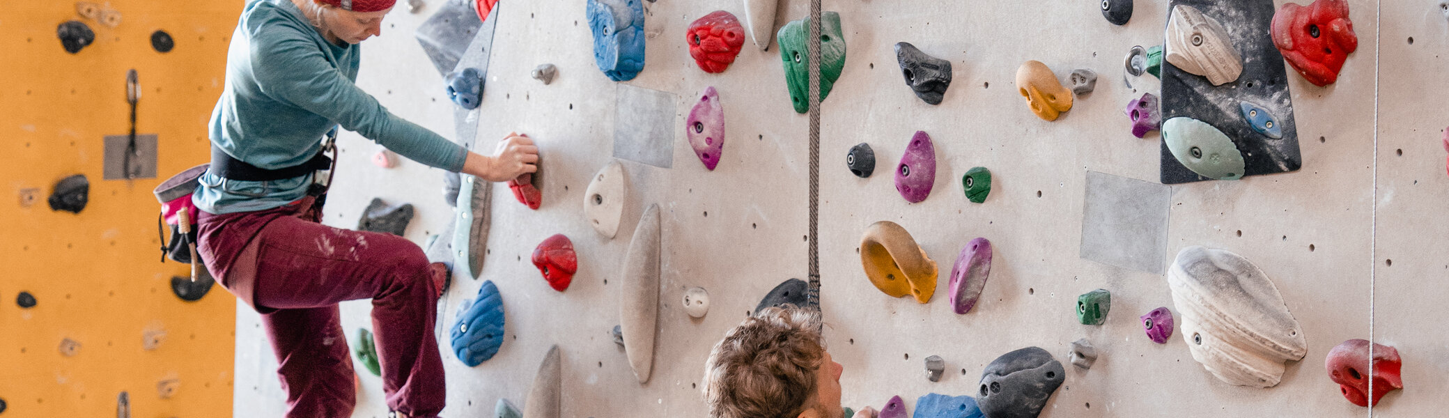 Zwei Personen bouldern nebeneinander an einer Boulderwand | © DAV/Marisa Koch